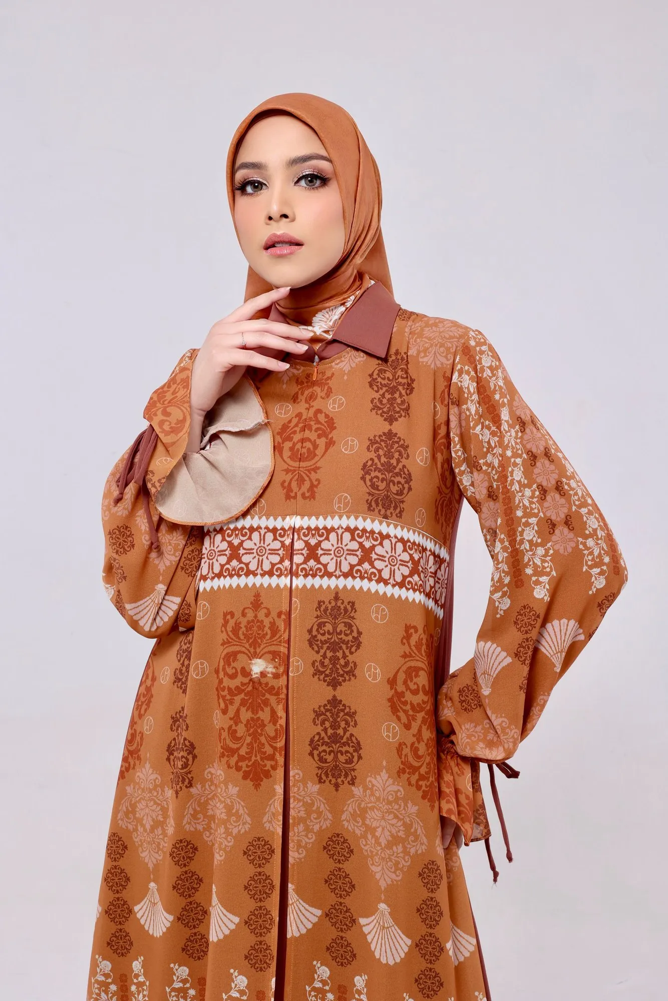Model mengenakan gamis terracotta dengan print ornamen